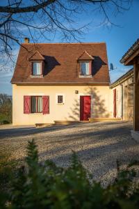 a white house with red doors on a road at Gîte de Caillou in Berbiguières