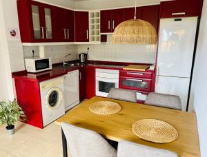 cocina con mesa de madera y armarios rojos en La Casa Nieves, en Lodero
