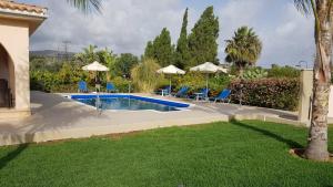 a swimming pool in a yard with chairs and umbrellas at The Arches Villa in Lachi