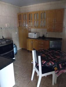 a kitchen with wooden cabinets and a table with a microwave at Casa de Fundo da Martinha in Campinas