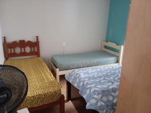a small room with two beds and a chair at Casa de Fundo da Martinha in Campinas