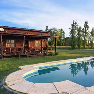a log cabin with a pool in front of it at Cabaña La Obsidiana in San Miguel del Monte