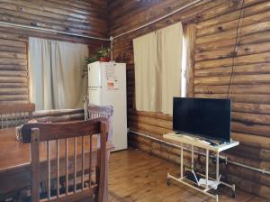 a room with a desk with a television and a refrigerator at Cabaña La Obsidiana in San Miguel del Monte