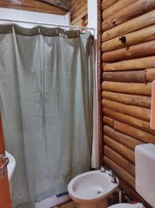 a bathroom with a shower curtain and a toilet at Cabaña La Obsidiana in San Miguel del Monte +5 photos