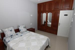 Un dormitorio con una cama y un armario de madera. en Villa Racine, en Porto Novo 2 fotos más