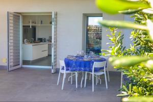 une table bleue avec des chaises blanches et une cuisine dans l'établissement La Casa diLà sul Mare, à Acireale