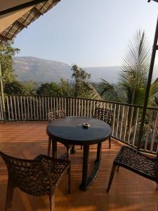 a table and chairs on a deck with a view at CharDara Agrotourism & FarmStay in Mahabaleshwar