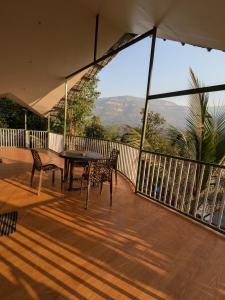 a balcony with a table and chairs and a view at CharDara Agrotourism & FarmStay in Mahabaleshwar