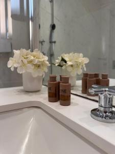 W łazience znajduje się blat z 2 wazami kwiatów i umywalka. w obiekcie Cristal - Neptun Park by OneApartments w Gdańsku