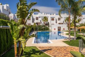 a large white building with a swimming pool and palm trees at Cathy in San Juan de los Terreros