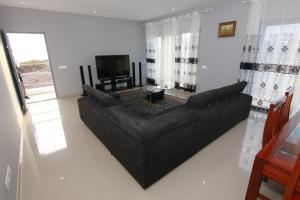 Una sala de estar con un sofá negro y un televisor. en Villa Racine, en Porto Novo