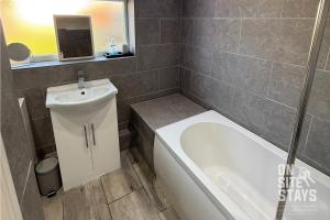 y baño con lavabo, bañera y aseo. en OnSiteStays - 4 bedroom house with 2 bathrooms, en Welling