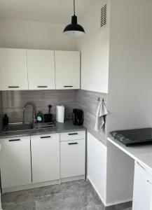 une cuisine avec des armoires blanches et un évier dans l'établissement Kawalerka Młodych Patriotów, à Gliwice