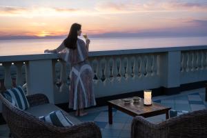 a woman standing on a balcony looking out at the ocean at Palace Hotel in Viareggio