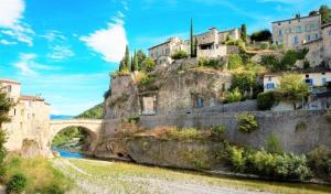 a bridge over a river with buildings on a mountain at LA VASIO Hypercentre Vaison-la-Romaine - Air-conditioned in Vaison-la-Romaine