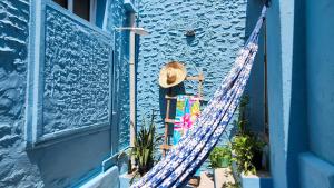 a person standing outside a blue building with a surfboard at Casa Andorinha in Lençóis