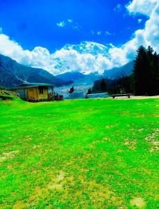 a field of green grass with mountains in the background at Fairy meadows BroadView Hotel in Tato +12 photos