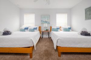 two beds in a room with two windows at Be A Nomad - Combined Home for Groups II - Steps to Ocean in Jacksonville Beach