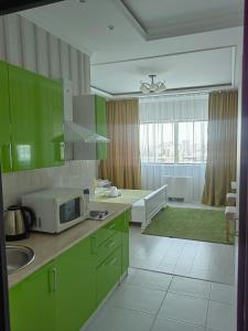 a kitchen with green cabinets and a microwave on a counter at 41-40 этаж Отель Bon Dian in Astana