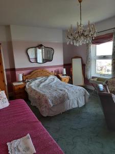 1 dormitorio con cama, espejo y lámpara de araña en Sea view flat at Claverton House, en Ryde