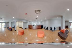 a large room with orange chairs and a wooden floor at OYO Hotel Orlando Airport in Orlando