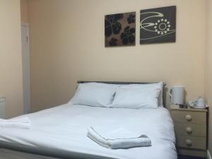 a bedroom with a white bed with two pictures on the wall at London Olympus Hotel in London