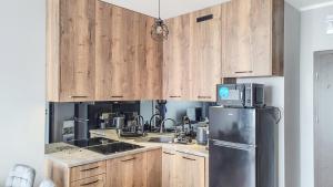 a kitchen with wooden cabinets and a stainless steel refrigerator at Apartament U Dziewczyn in Gąski