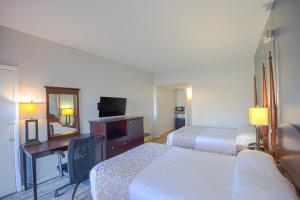 a hotel room with two beds and a desk and a television at Sunrise Inn by OYO Titusville FL in Titusville