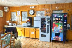 a kitchen with a refrigerator and a clock on the wall at Super Inn & Suites by OYO Milledgeville in Milledgeville