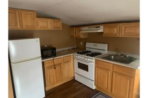 eine Küche mit weißen Geräten und Holzschränken in der Unterkunft Werry's Cottages and Pub By OYO East Stroudsborg - Weekly Stays in East Stroudsburg