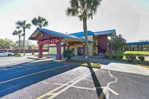 a building with a palm tree in a parking lot at OYO Hotel Pensacola I-10 & Hwy 29 in Pensacola
