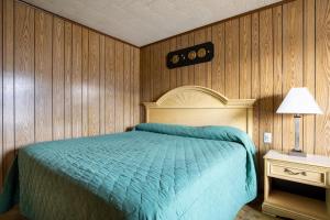 1 dormitorio con 1 cama azul y paredes de madera en OYO Hotel Holly Springs MS, en Holly Springs