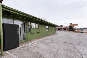 un edificio verde con una puerta en un estacionamiento en OYO Hotel Holly Springs MS, en Holly Springs