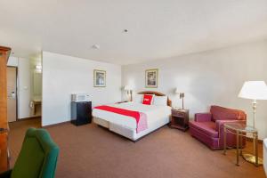 a hotel room with a bed and two chairs at OYO Hotel Portage I-94 in Portage