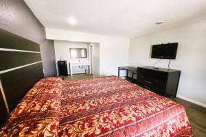 a hotel room with a bed and a flat screen tv at Travel Inn by OYO, Hwy 80 - Jackson in Jackson
