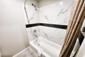a bathroom with a white tub and a white marble shower at Travel Inn by OYO, Hwy 80 - Jackson in Jackson +9 photos