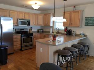 a kitchen with wooden cabinets and a large island with bar stools at Roof-Top Deck With Ocean & Bay Views Single Family Beach Badges Private Yard Ping Pong And Pool Table Wifi 1 Block From Ocean 15 Blocks To Bay in Ship Bottom