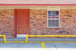 a brick building with a red door and a window at Economy Inn By OYO Lockport near Houma in Lockport