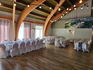 a banquet hall with white tables and chairs and a large screen at La Route d'Argent in Bozouls
