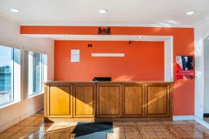 an office with an orange wall and wooden cabinets at OYO Townhouse Dodge City KS in Dodge City +20 photos