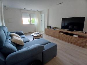 a living room with a blue couch and a flat screen tv at Moderno apartamento en La Manga Club in Atamaría