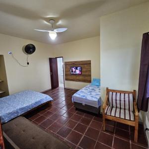 a room with two beds and a chair in it at KITNET Beira Mar Prainha Barra - Rio das Ostra in Barra de São João