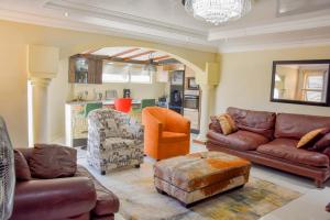 a living room with leather furniture and an open kitchen at Modern Delux 2 Bedroom Townhouse in Bloemfontein