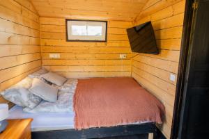 a small room with a bed in a log cabin at Meža namiņš Upeskrasti in Zosuļi