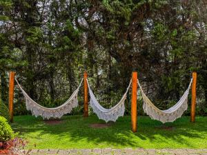 two hammocks on poles in the grass under a tree at Pousada Victoria Villa By Nacional Inn - A 800 metros da Vila Capivari in Campos do Jordão