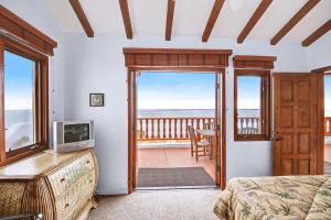 a bedroom with a bed and a television and a balcony at H230 - Hamilton Cove Villa 2-30 in Avalon