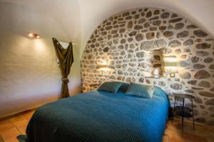 a bedroom with a blue bed in a stone wall at Domaine le C4 - restaurant et gîte d'exception familial avec terrasse Ardèche in Casteljau +25 photos