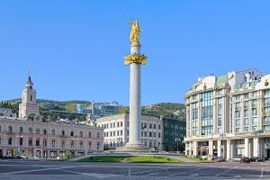 a pole in the middle of a city with buildings at Behind the Parliament Building in Tbilisi City