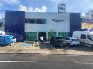 累西腓Hotel Enseada Aeroporto的一栋建筑物,停车场里停着几辆车