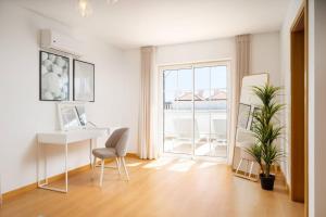 a white room with a desk and a chair and a window at Fresh & Breezy Tavira Apartment in Cabanas de Tavira